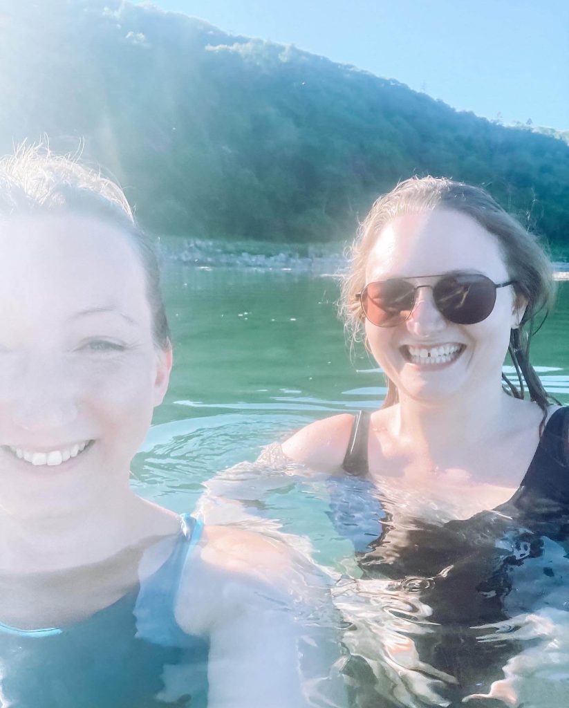 A smiling selfie of Estelle and Lauren in calm water on a sunny day.