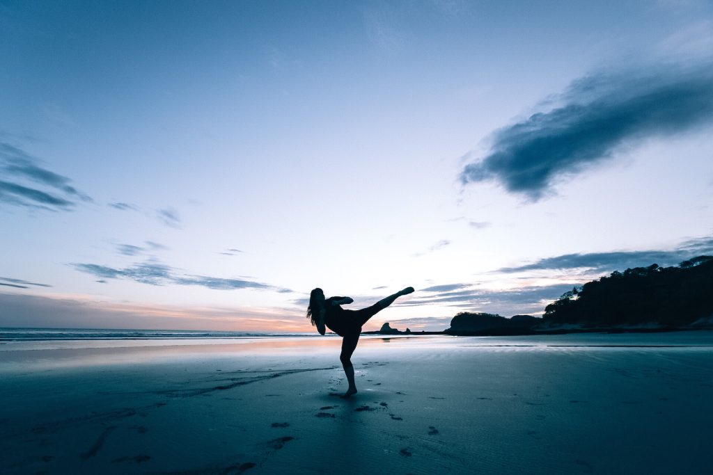 Silhouette of a woman kickboxing on a beach
